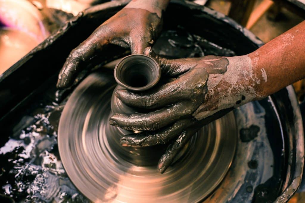 Mãos masculinas moldando vaso.