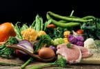 Vários legumes e vegetais dispostos numa mesa.