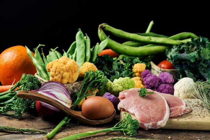 Vários legumes e vegetais dispostos numa mesa.