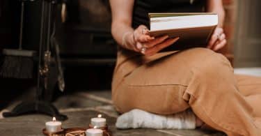 Mulher segurando livro com velas ao seu lado