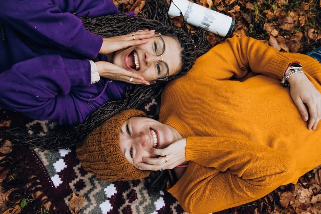 Duas mulheres deitadas viradas para cima, elas estão sorrindo.