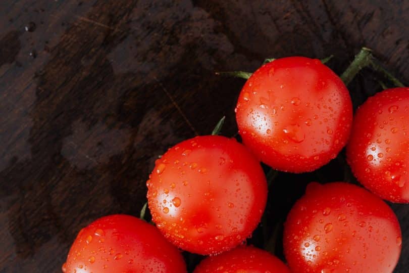 Tomates molhados em uma superfície de madeira.