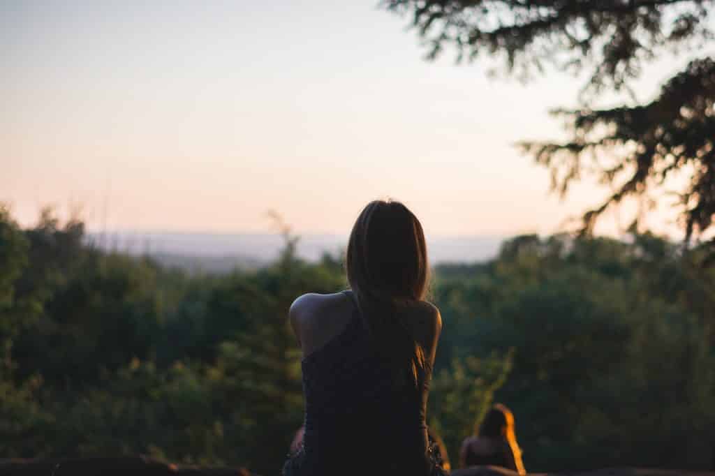 Mulher sentada olhando para um pôr-do-sol