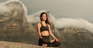 Mulher branca sentada meditando.