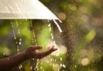 Uma mão feminina estendida. Ao fundo, chuva.