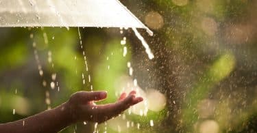 Uma mão feminina estendida. Ao fundo, chuva.