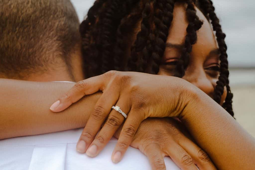 Mulher negra abraçando homem.