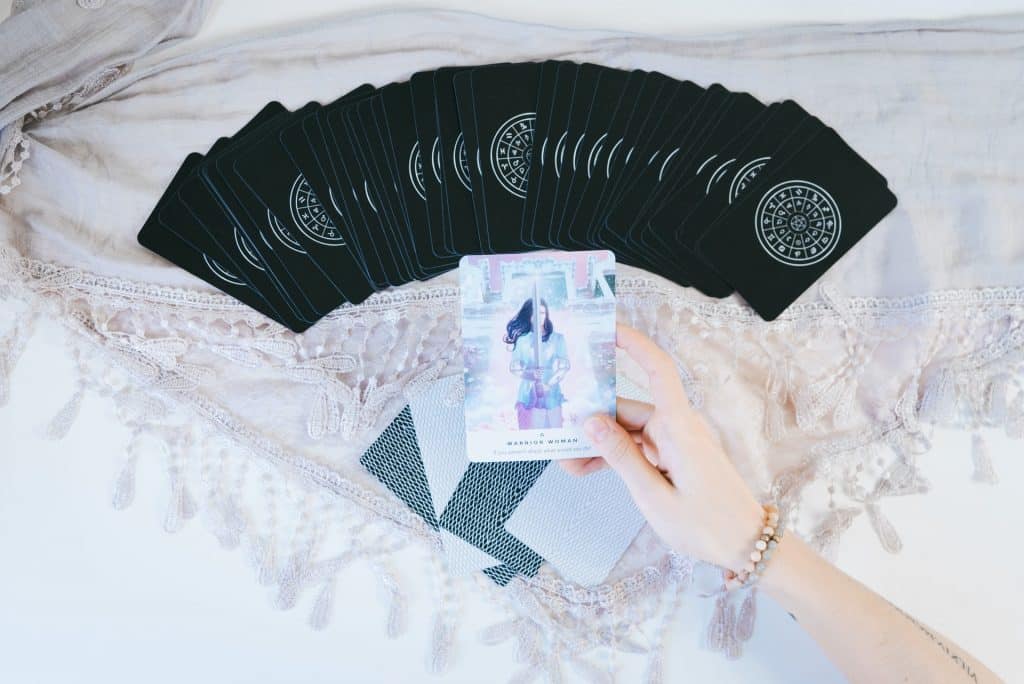 Mulher branca segurando cartas de tarot.