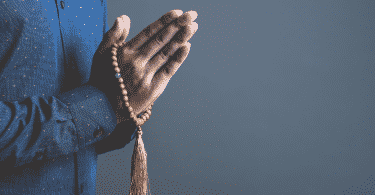 pessoa orando com terço nas mãos