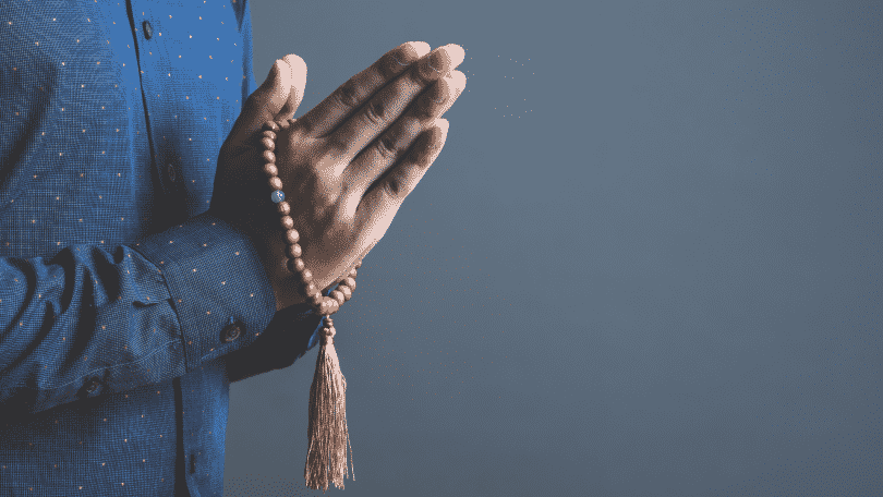 pessoa orando com terço nas mãos