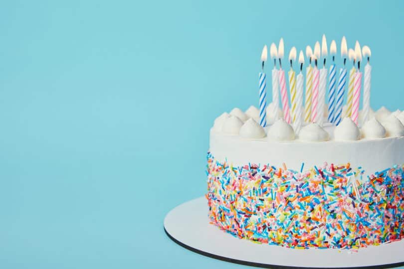 Bolo de aniversário cheio de granulados coloridos e velas.