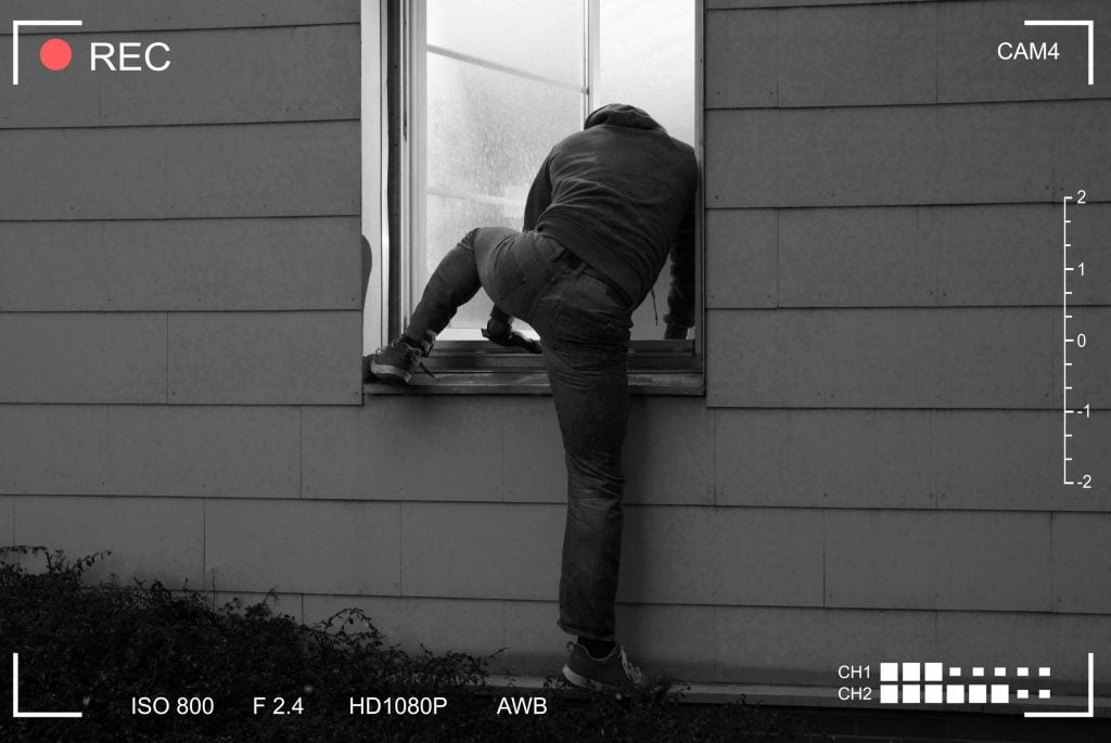 Homem entrando pela janela de uma casa.