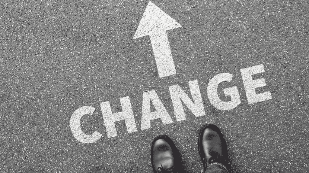 Asfalto grafado com uma seta à frente da palavra "change", também escrita no asfalto. 