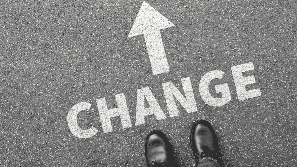 Asfalto grafado com uma seta à frente da palavra "change", também escrita no asfalto.
