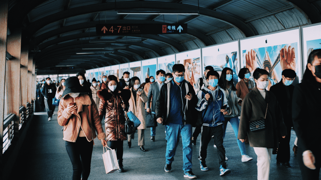 Diversas pessoas de máscara andando em um terminal