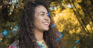 Mulher sorrindo com bolhas de sabão flutuando em um parque