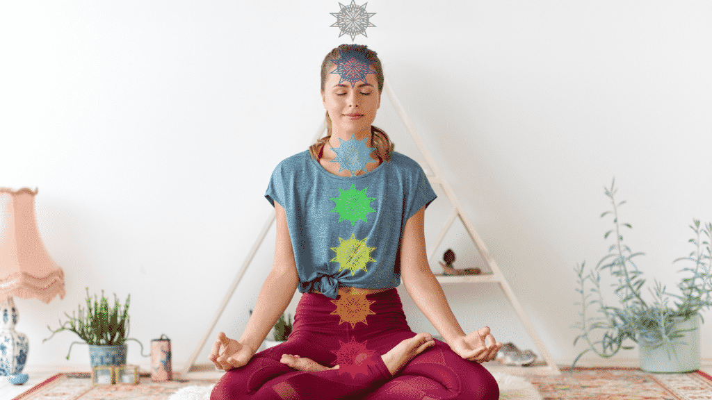 Mulher em posição de meditação. Os sete chakras estão alinhados em suas posições pelo corpo dela