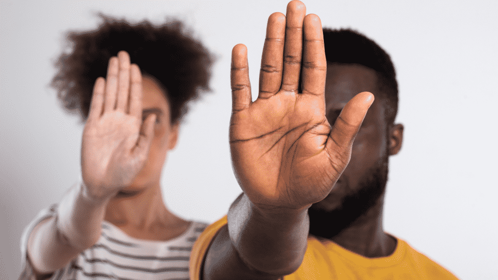 À esquerda, uma mulher negra erguendo sua mão direita e, ao mesmo tempo, mostrando sua palma à câmera. À direita, um homem negro realizando a mesma postura. Este gesto é conhecido, popularmente, como "pare".