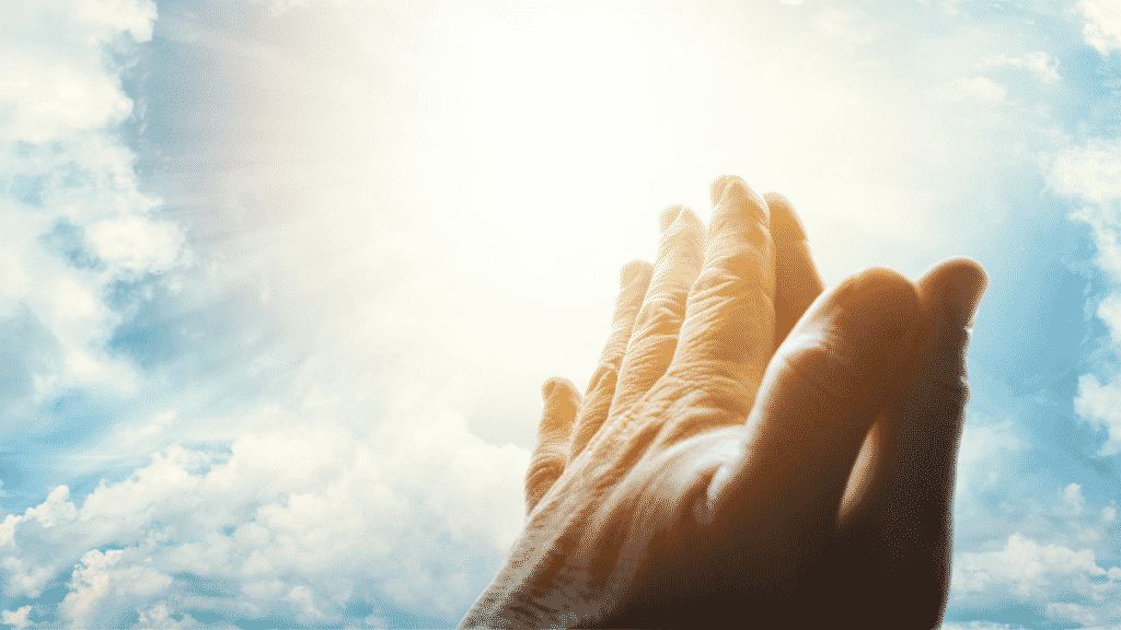 Mãos erguidas ao céu em gesto de oração.