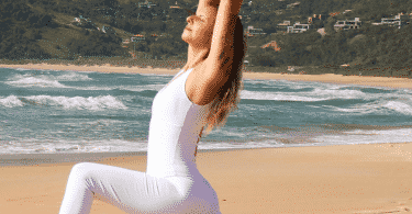 Mulher fazendo alongamento de Yoga na praia.