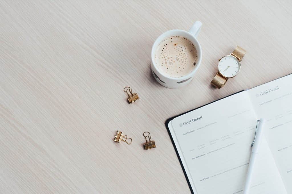 Caderno, prendedores e caneca de café.