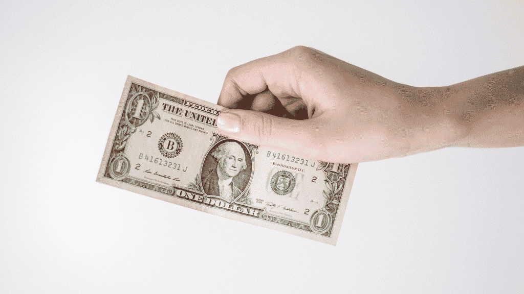 Uma mão segurando uma nota de dólar.