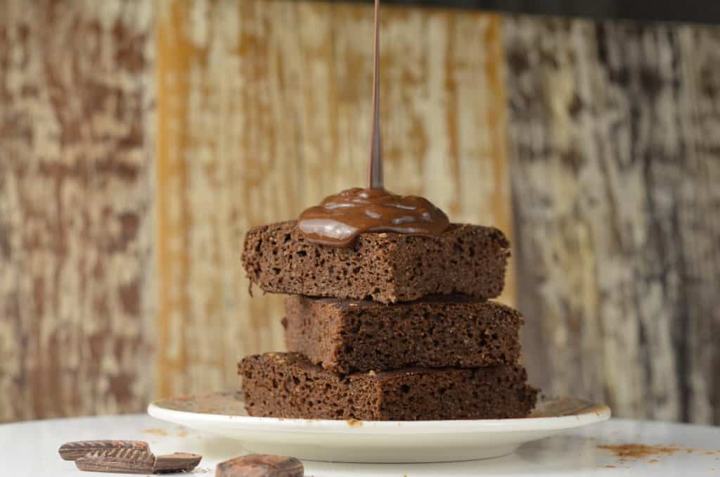 Pedaços de bolo de chocolate com uma calda caindo em cima.