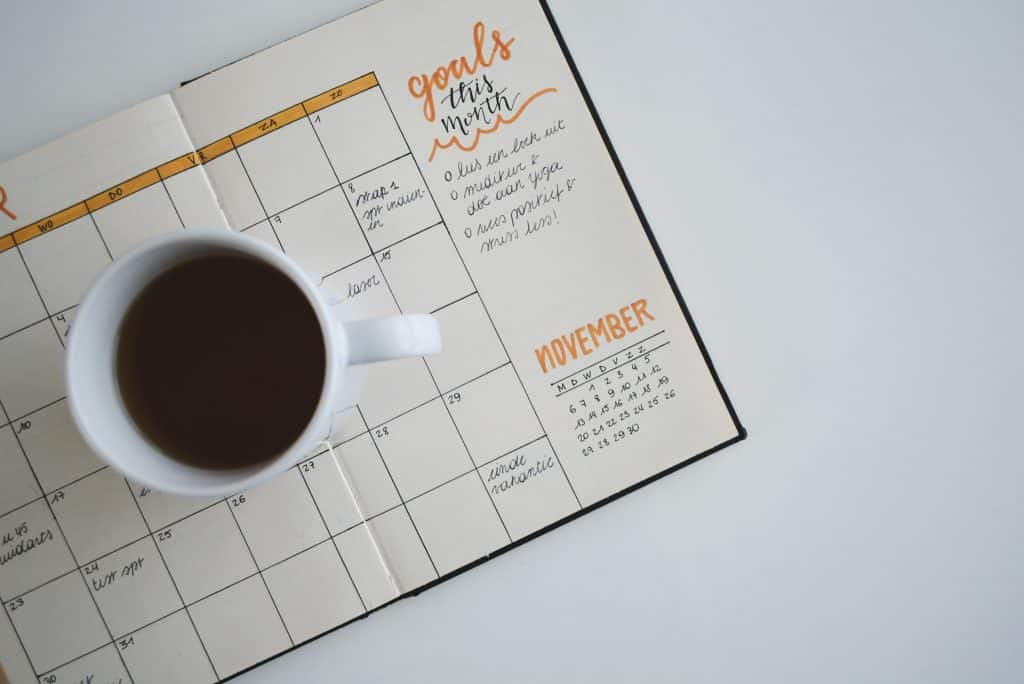 Agenda aberta com uma xícara de café no meio.