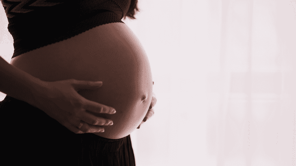 Uma mulher grávida mostrando sua barriga.