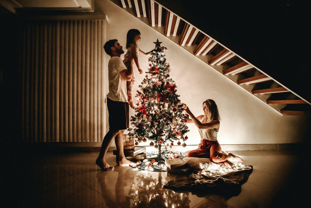 Homem, mulher e menina brancos montando árvore de natal.