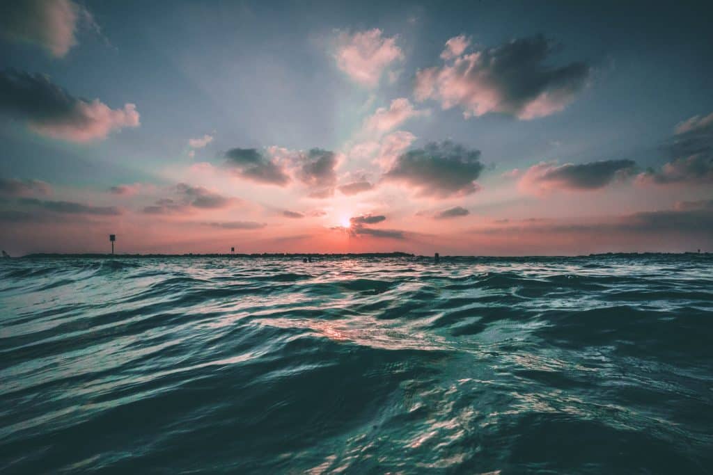 Foto do mar com um pôr do sol ao fundo.