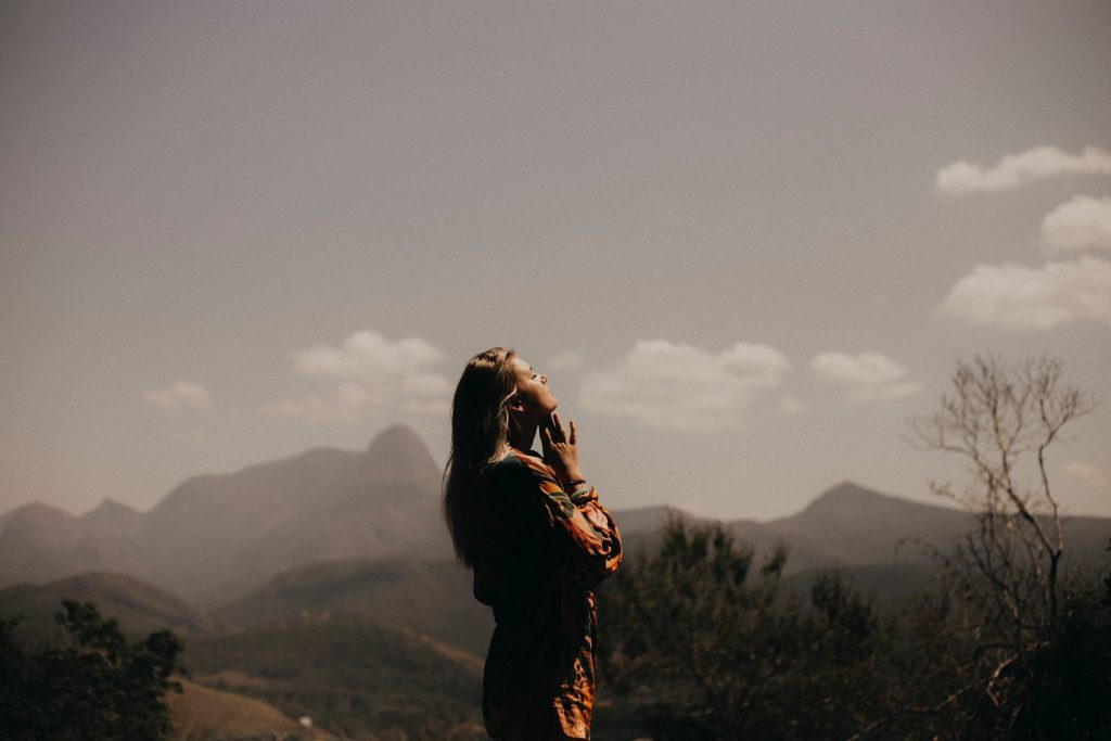 Mulher rezando em um ambiente montanhoso.