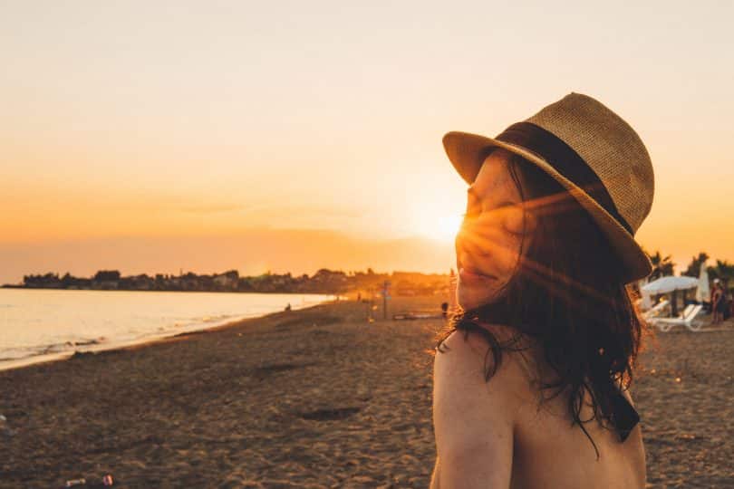 Jovem branca de olhos fechados e sol no rosto.