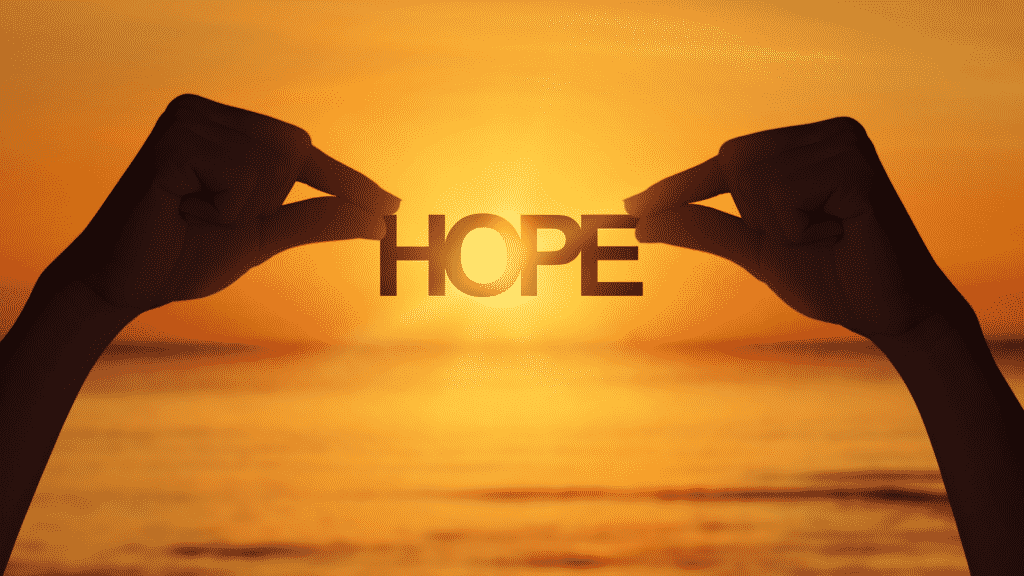 Mãos segurando letras que formam a palavra "hope".