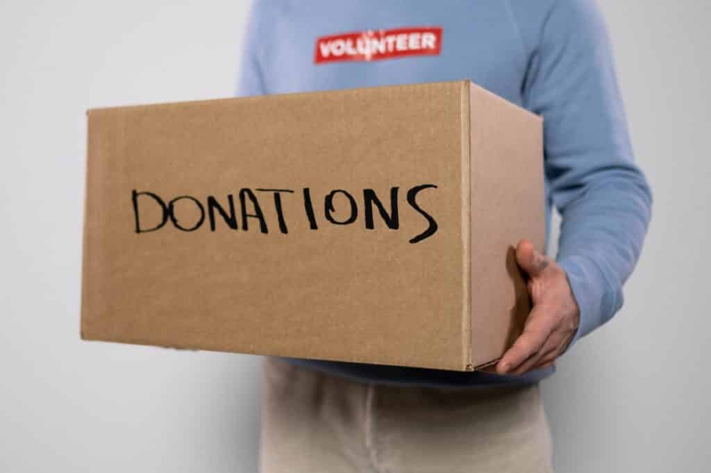 Homem negro segurando caixa escrito "donations".
