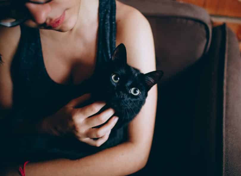 Mulher segurando um gato preto.