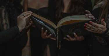 Mulheres segurando um livro de bruxaria.
