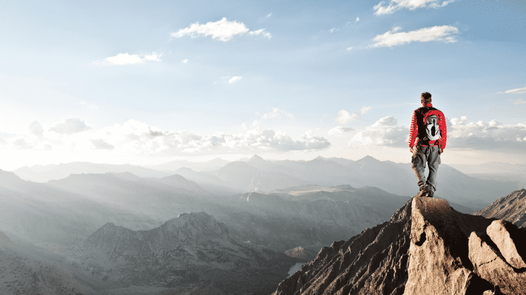 Um homem de pé no topo de um cume montanhoso.