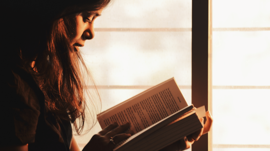 Mulher segurando um livro com as duas mãos enquanto o lê