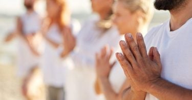 Grupo de pessoas fazendo namastê na praia