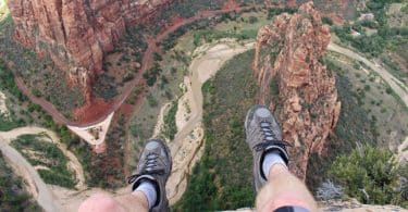 Homem sentado numa rocha no topo de um lugar natural muito alto