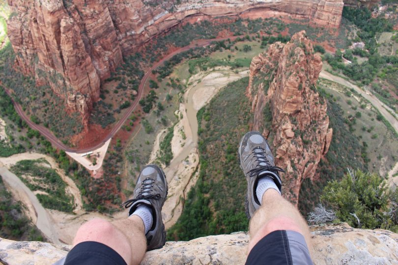 Homem sentado numa rocha no topo de um lugar natural muito alto
