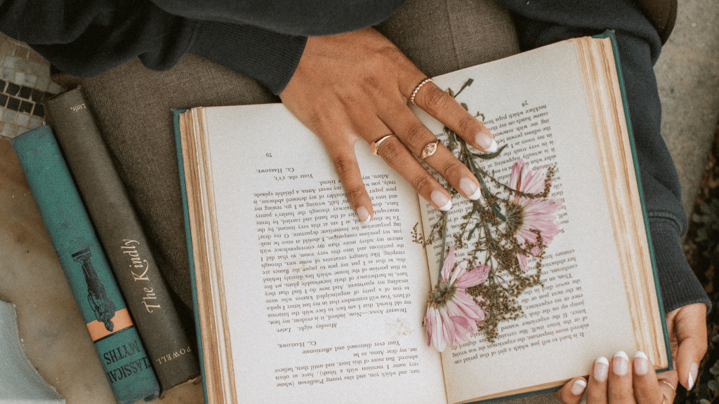 Mãos segurando um livro com uma flor dentro dele