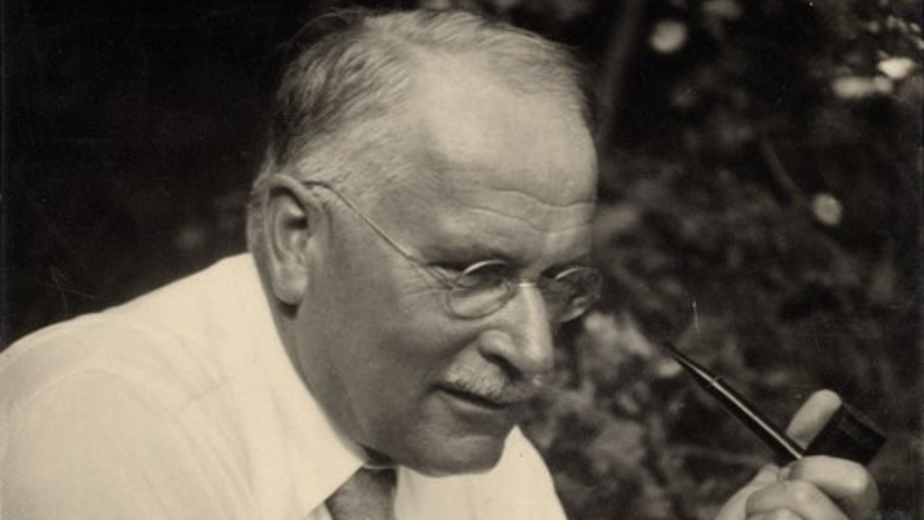 Uma fotografia de Carl Gustav Jung. Ele segura um cachimbo. 