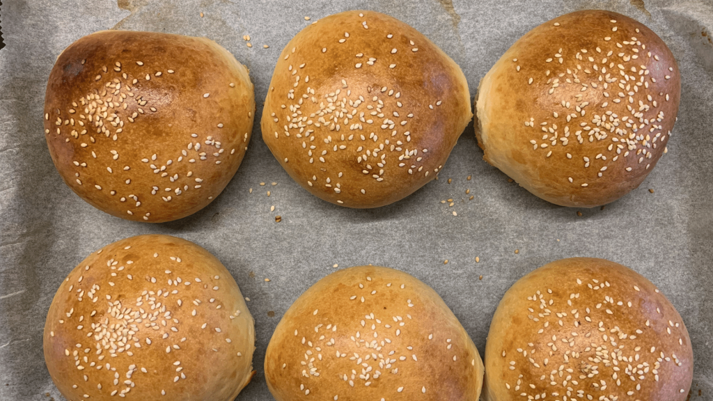 Seis pães de hambúrguer assados sobre uma superfície