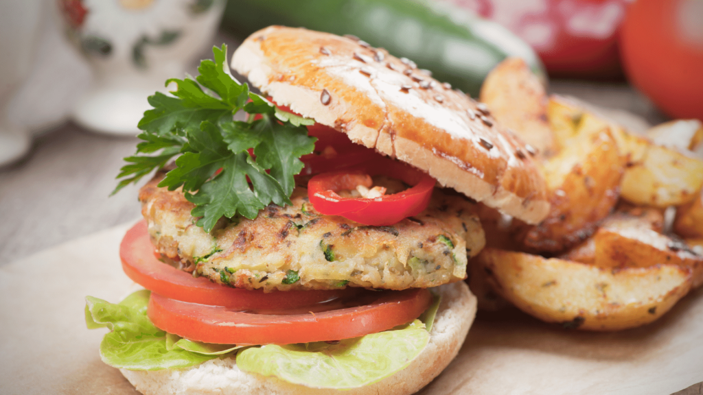 Lanche recheado com hambúrguer de grão-de-bico, alface e tomate com batatas-fritas rústicas ao lado