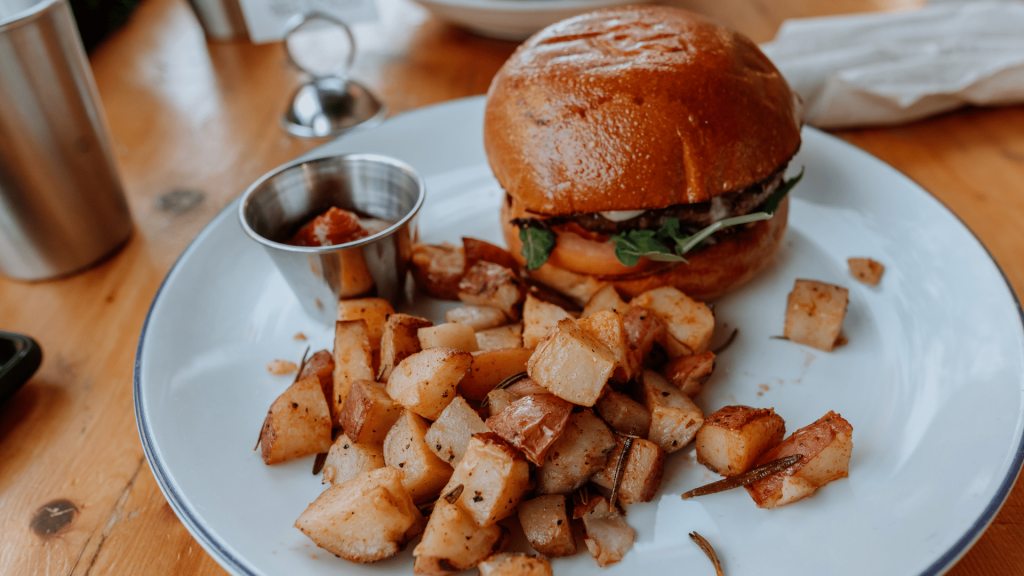 Prato contendo um lanche vegano, batata-frita rústica e ketchup