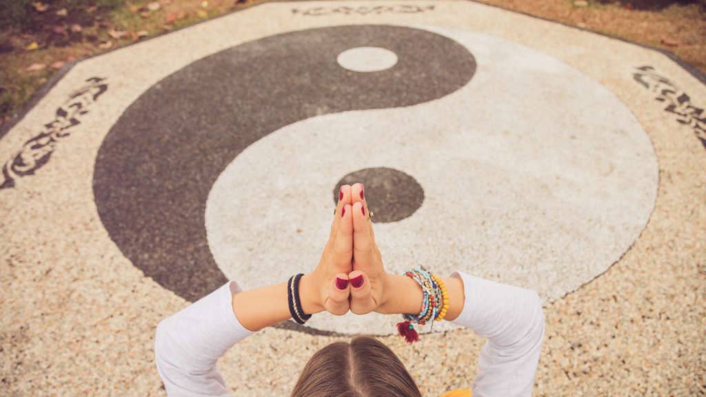 Um círculo de pedregulhos que forma o símbolo yin yang. Neste círculo, uma mulher meditando.