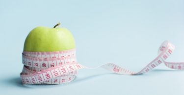 Uma fita métrica mensurando uma maçã-verde.