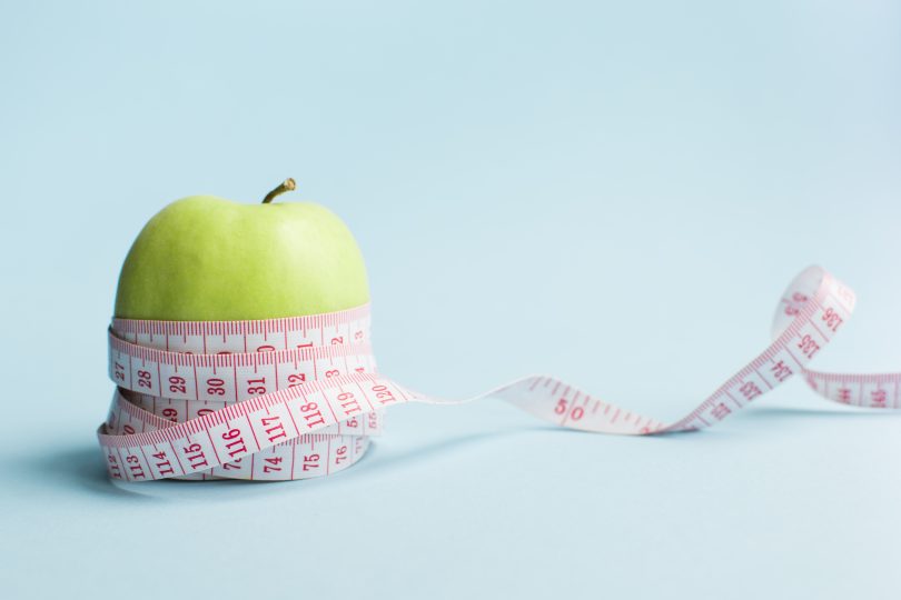 Uma fita métrica mensurando uma maçã-verde.